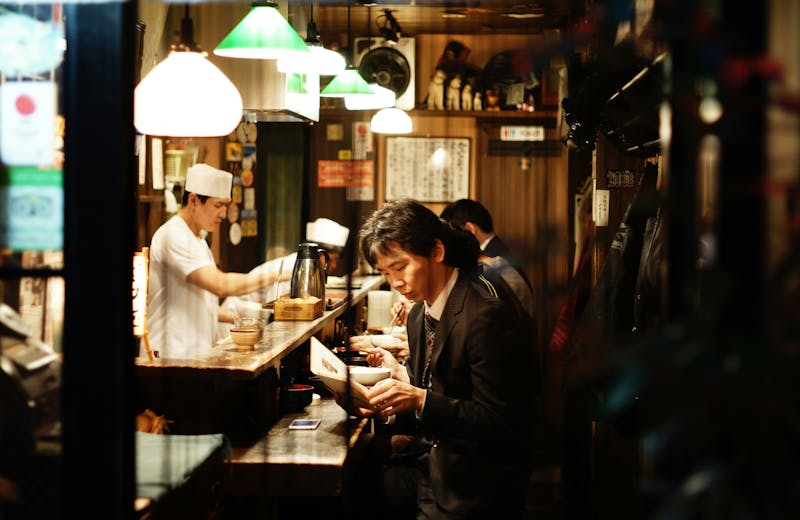 A man eating at a traditional Japanese restaurant sitting at the bar