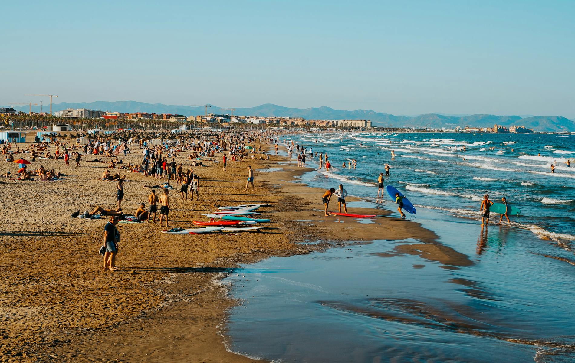 andy brown shoreline of La Patacona Beach in Valencia, with gentle Mediterranean waves and a wide open sky.