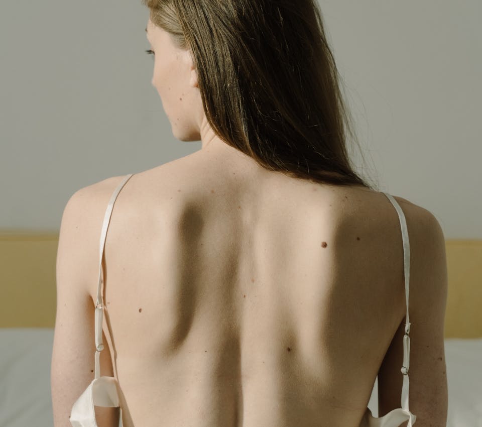 back of light skin ton female model with hair over her shoulder looking down to the side