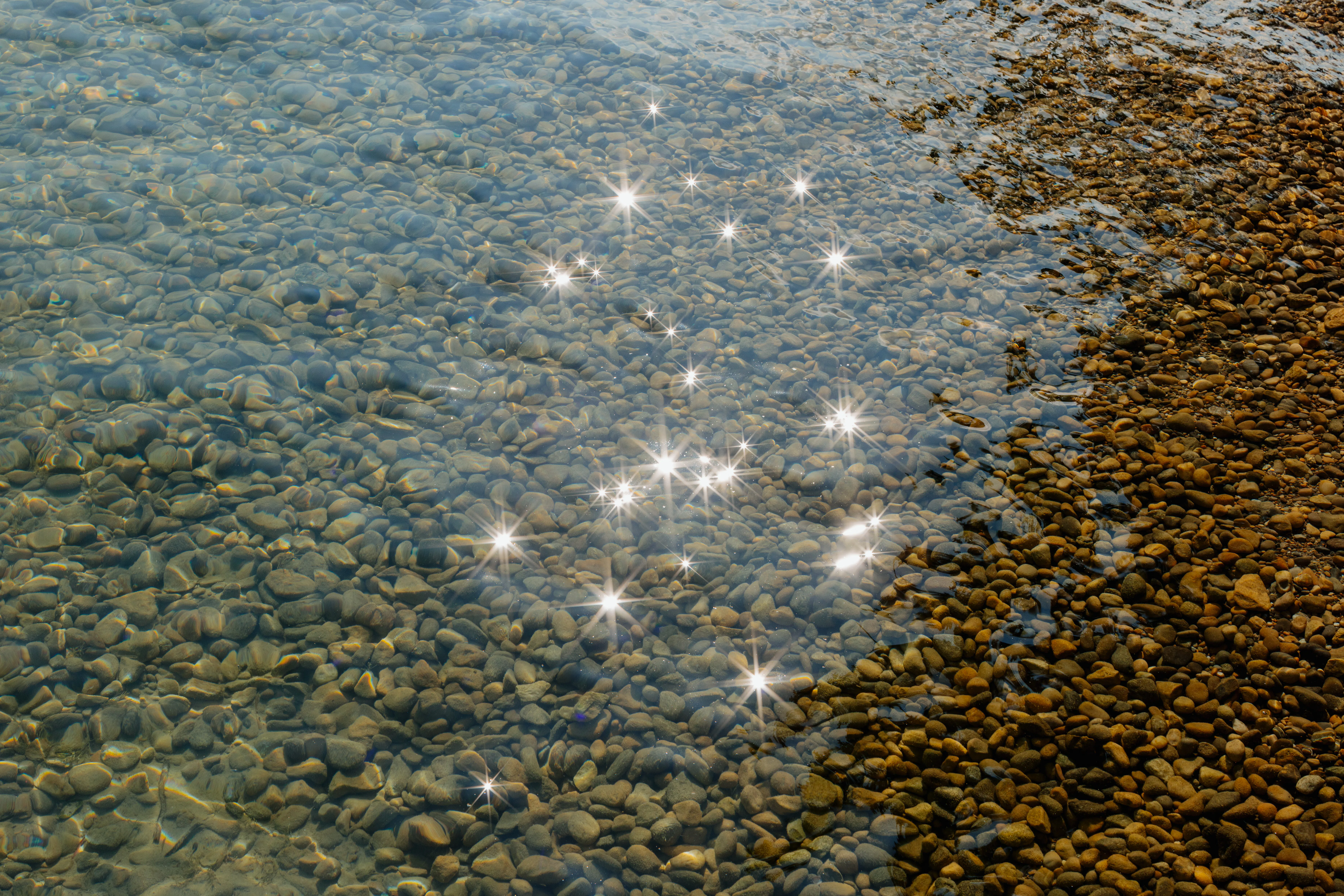 Wasser eines Sees glitzert mit Reflektion der Sonne