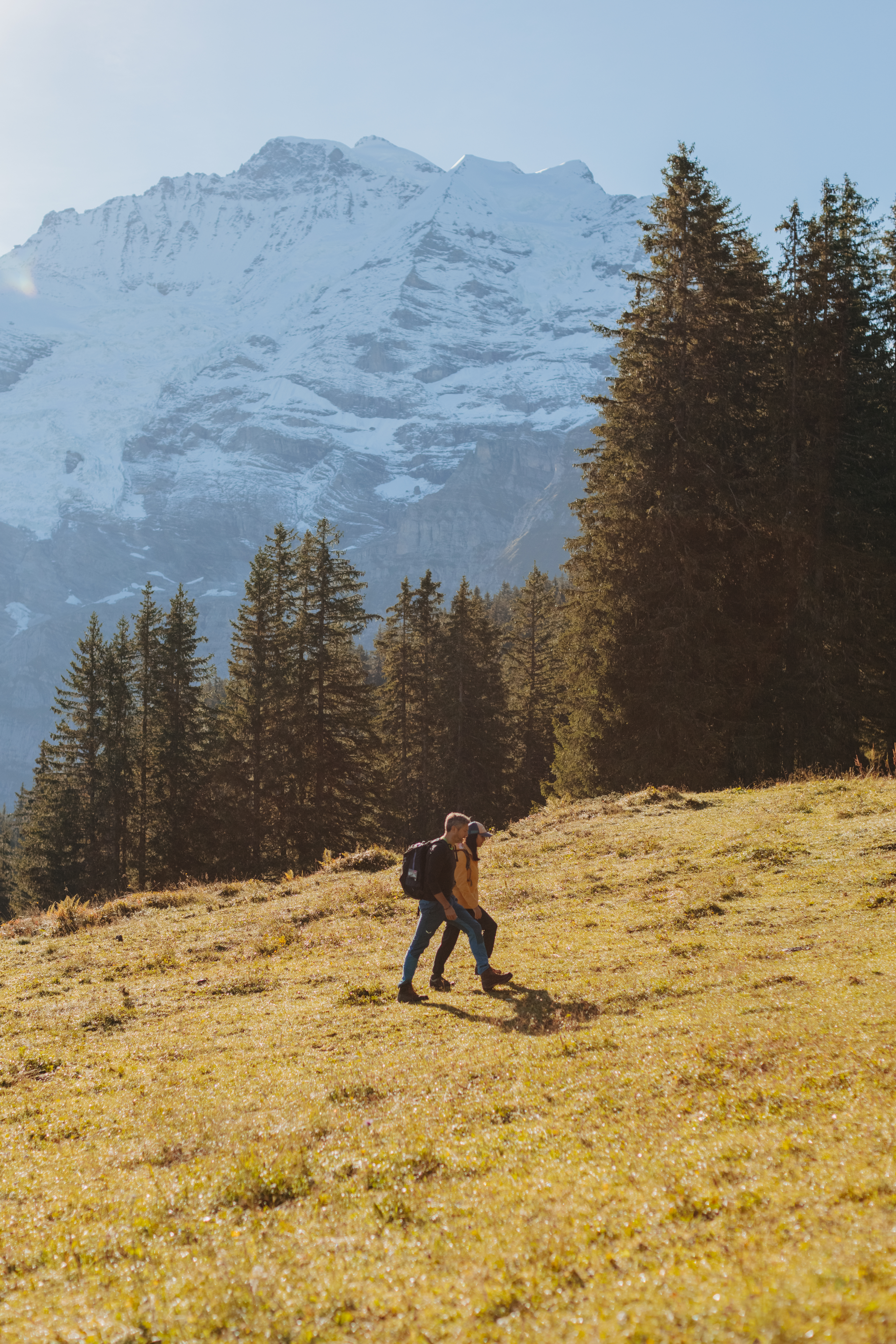 Paar beim Wandern mit schneebedeckten Bergspitzen im Hintergrund