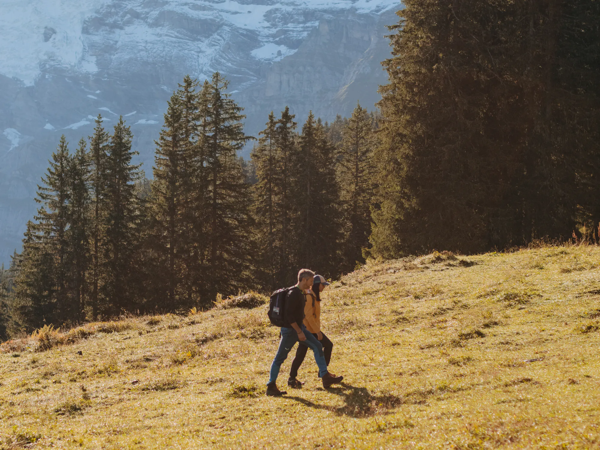 Paar beim Wandern mit schneebedeckten Bergspitzen im Hintergrund
