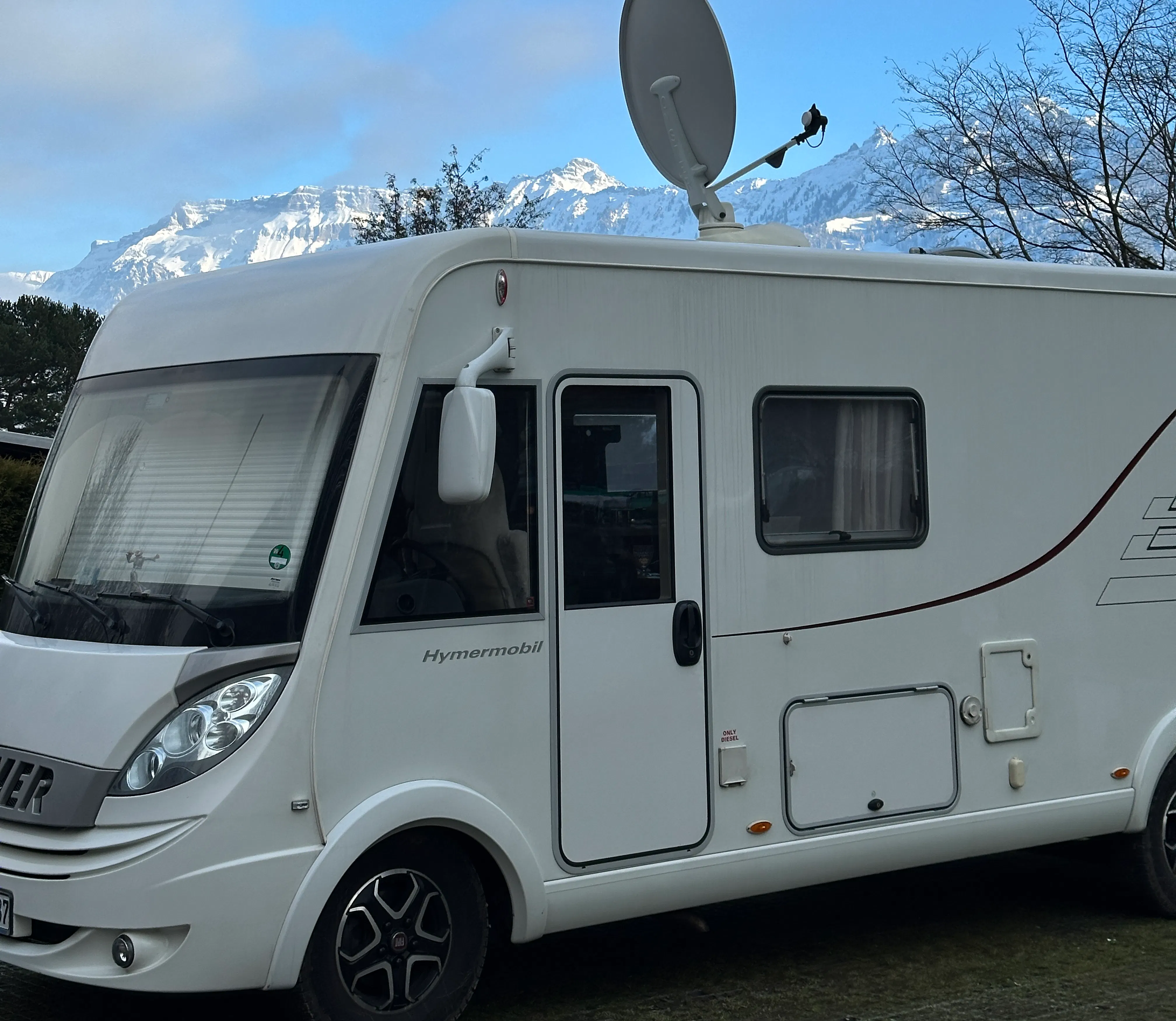 Camper auf Wintersaisonplatz mit Bergen im Hintergrund