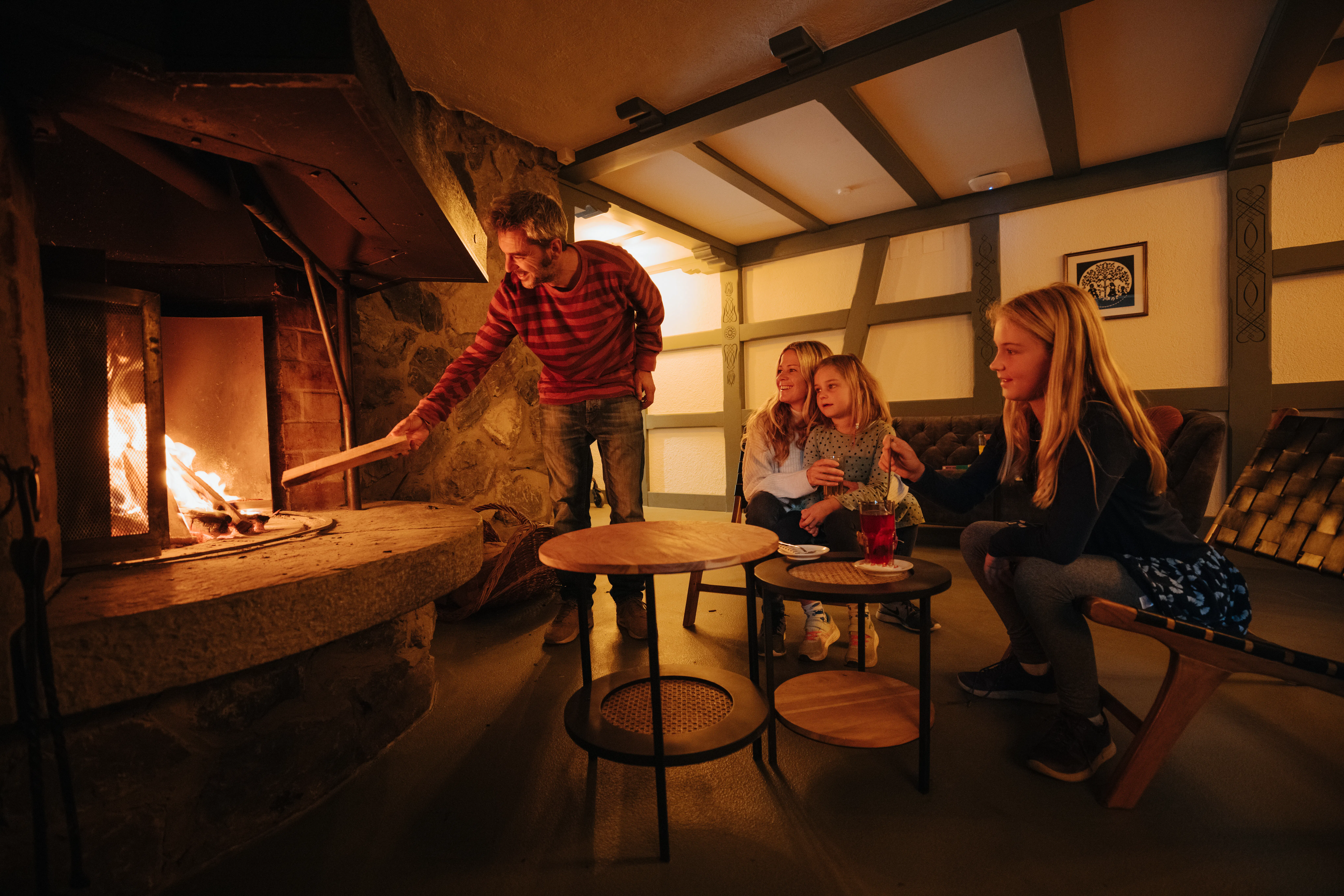 Familie vor dem Feuer in der Lounge auf dem Campingplatz Jungfrau