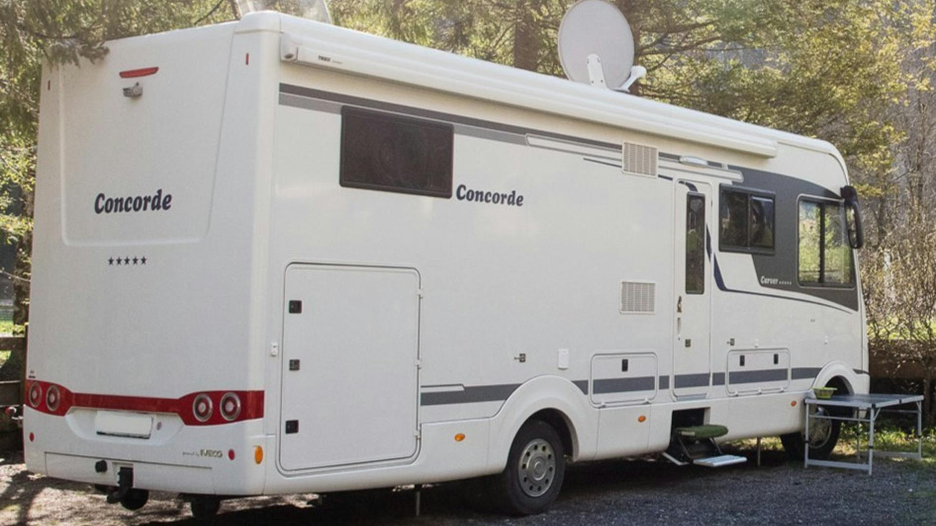 Grosses Wohnmobil mit Antenne und Tisch draussen