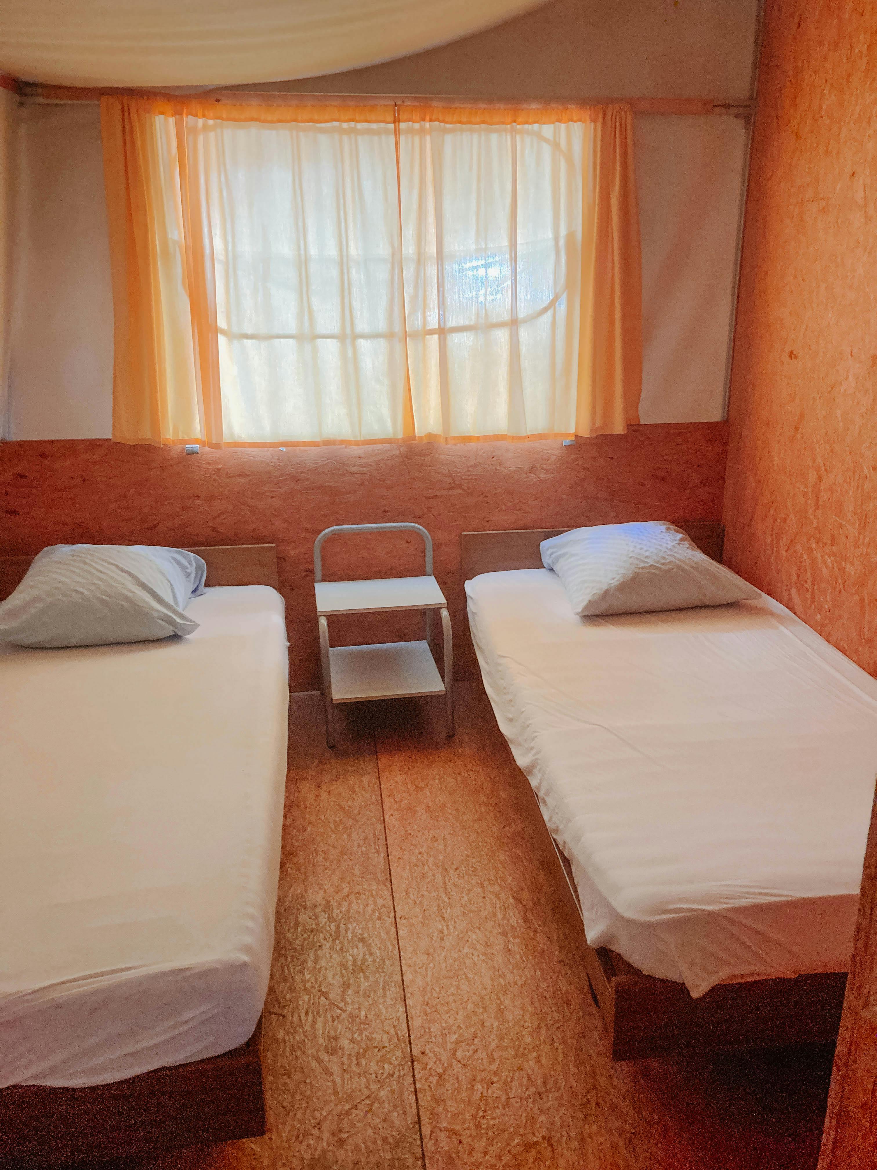 Zimmer des Familienzeltes mit zwei Einzelbetten und kleinem Nachttisch dazwischen