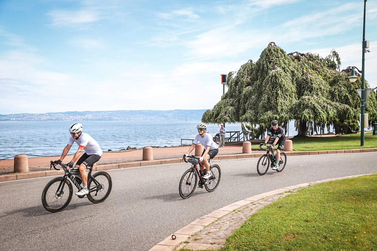Drei Velofahrer auf der Strasse neben dem Genfersee bei der Tour de Leman