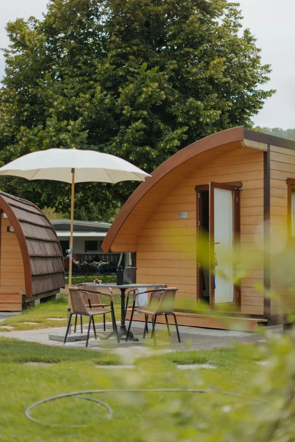 Alojamiento de alquiler «Beach Cabin» visto desde el exterior, con una pequeña terraza equipada con mesa, sillas y sombrilla