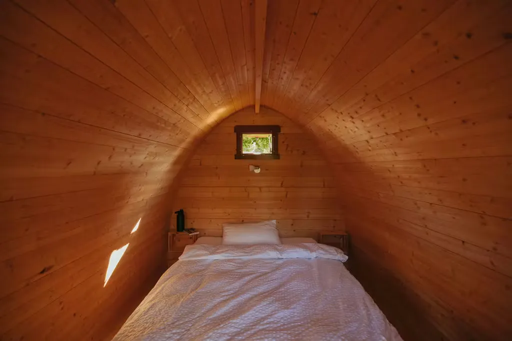 Innenansicht des Beach Hut auf dem Camping Erlach mit einem Doppelbett und einem kleinen Fenster an der Rückwand