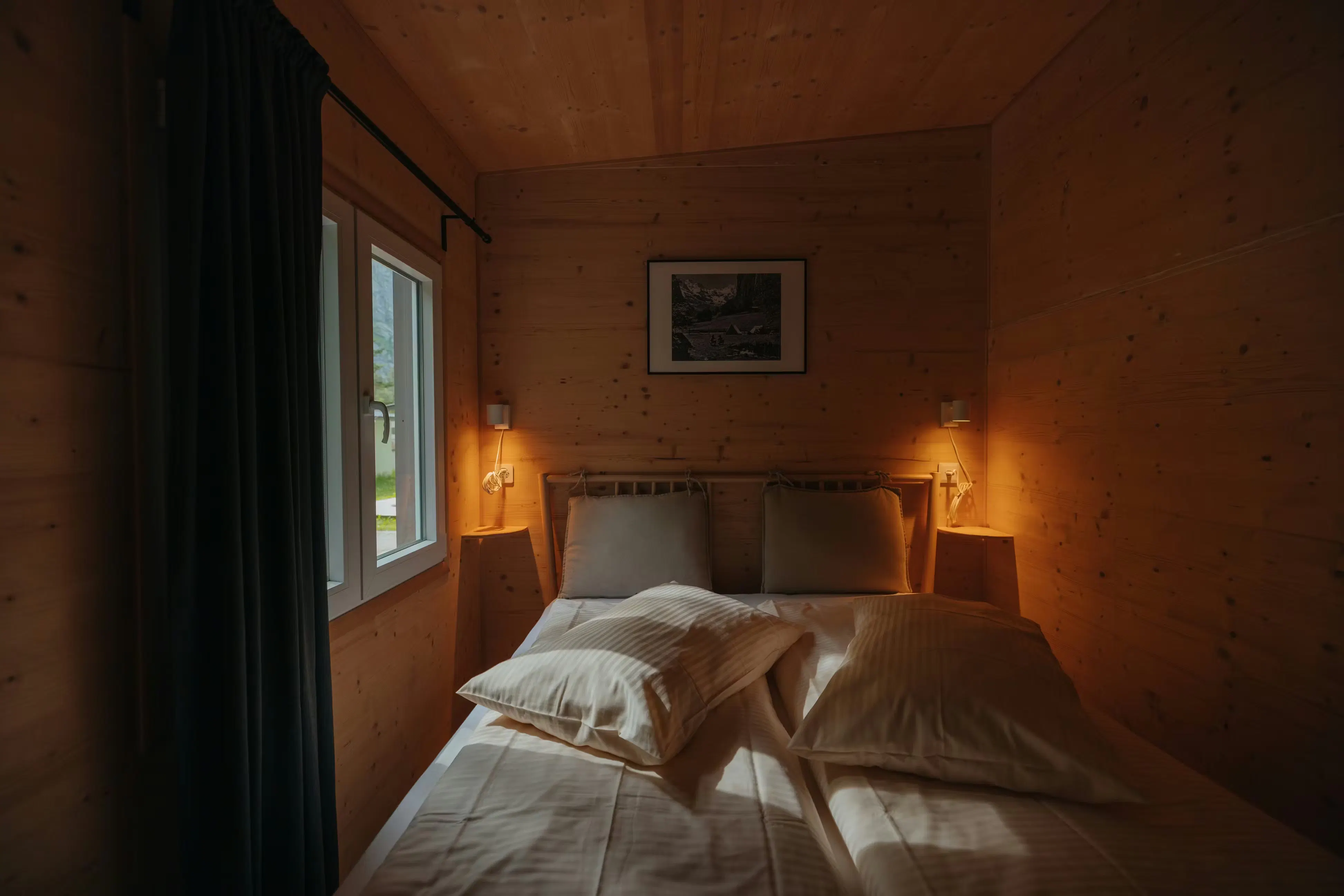 Schlafzimmer mit Holzwänden und bequemem Bett in der Mietunterkunft auf Camping Jungfrau