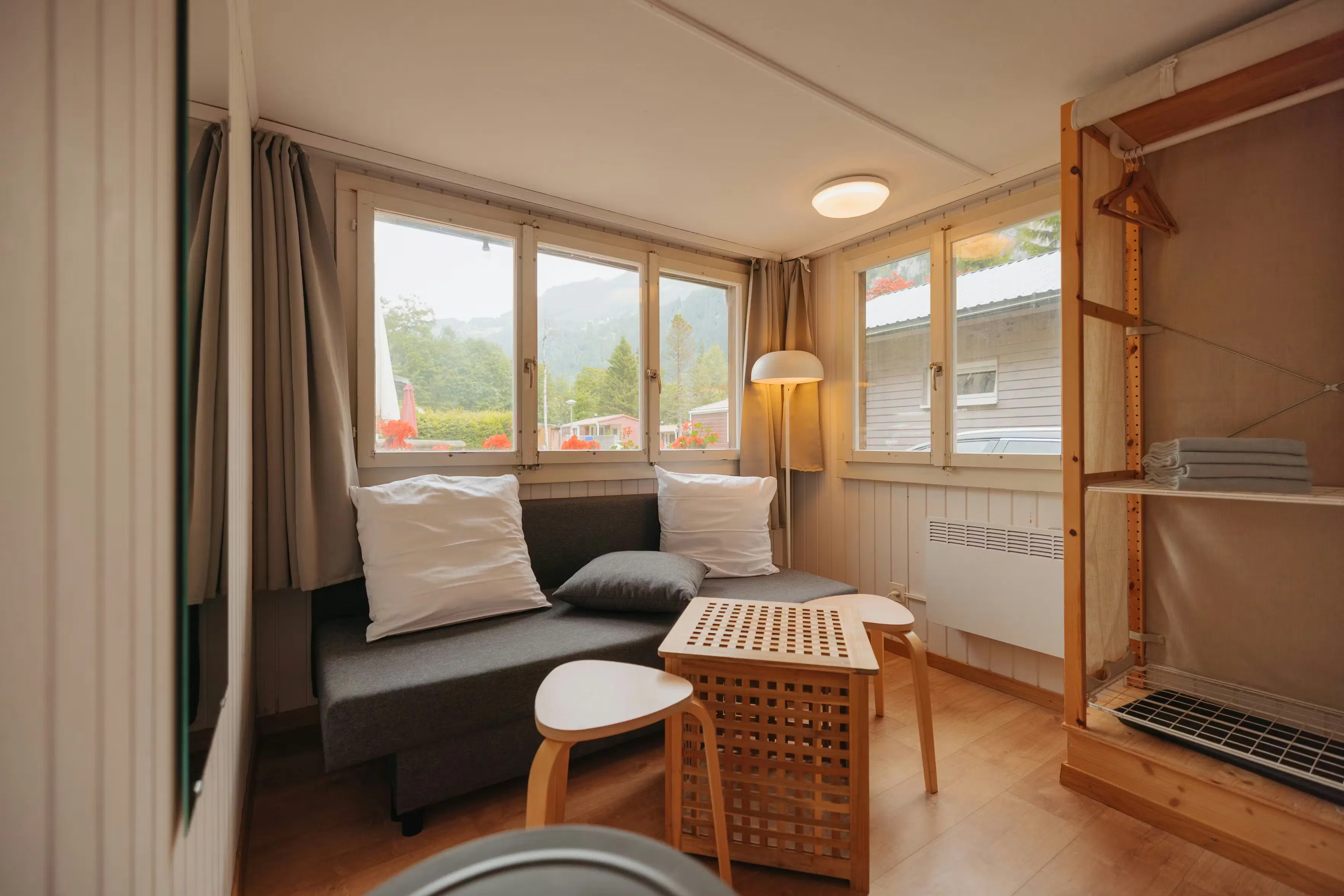 Innenraum der Eigerhütte auf Camping Jungfrau mit Garderobe vorne und Sofa und Licht hinten
