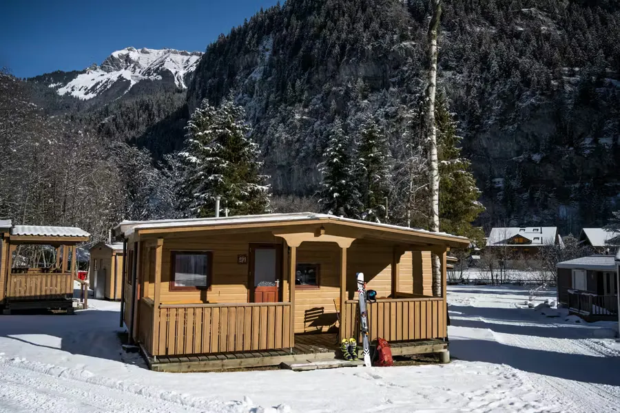 Mietunterkunft Mobilheim Jungfrau aus Holz mit verschneiter Umgebung und Bergen im Hintergrund