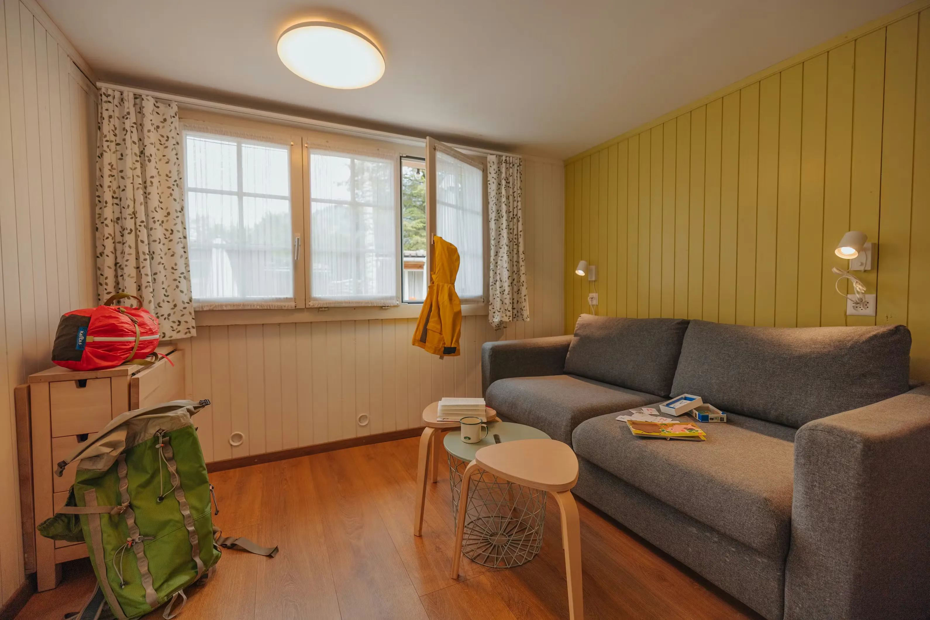 Wohnzimmer der Familienhütte mit einem Sofa und einem Sofatisch mit zwei Hockern