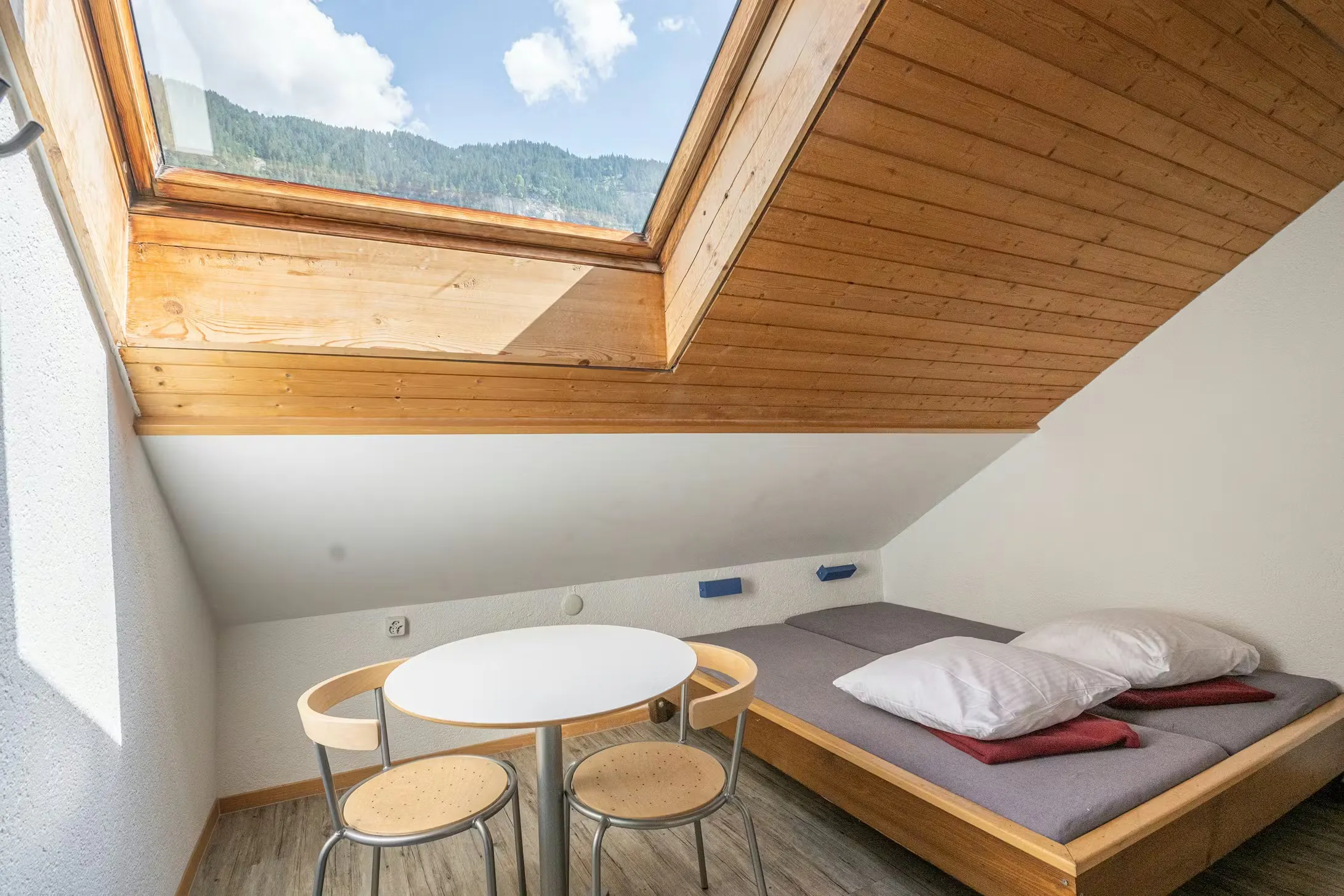 Herbergszimmer im Camping Jungfrau für zwei Personen mit Dachfenster und einem Tisch mit zwei Stühlen