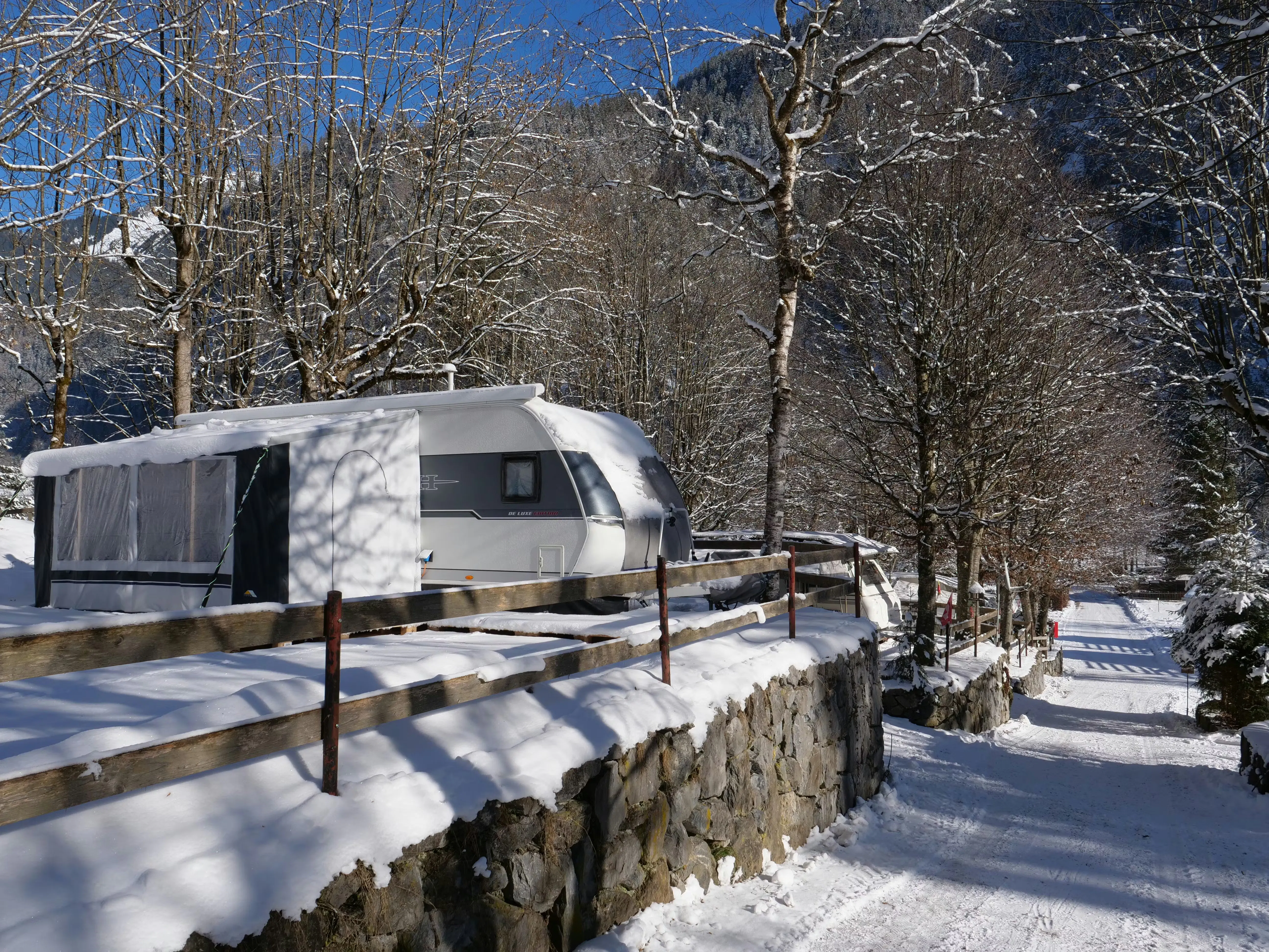 Wohnwagen mit Vorzelt auf Terrassen-Stellplatz im Winter auf dem Camping Jungfrau