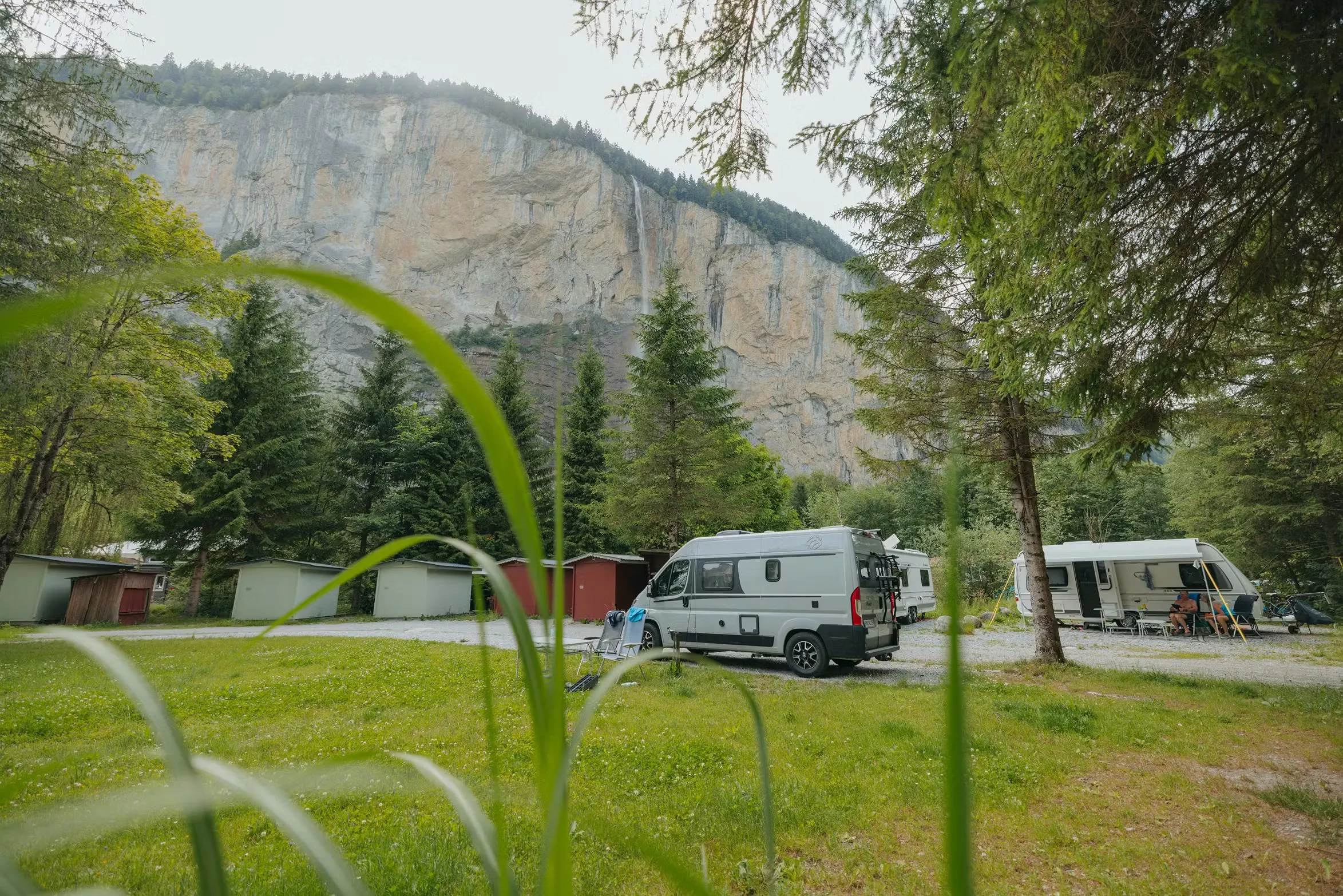 Van auf einem Classic Stellplatz auf Camping Jungfrau mit den Fuchsbau-Unterkünften dahinter und dem Staubbach-Wasserfall im Hintergrund