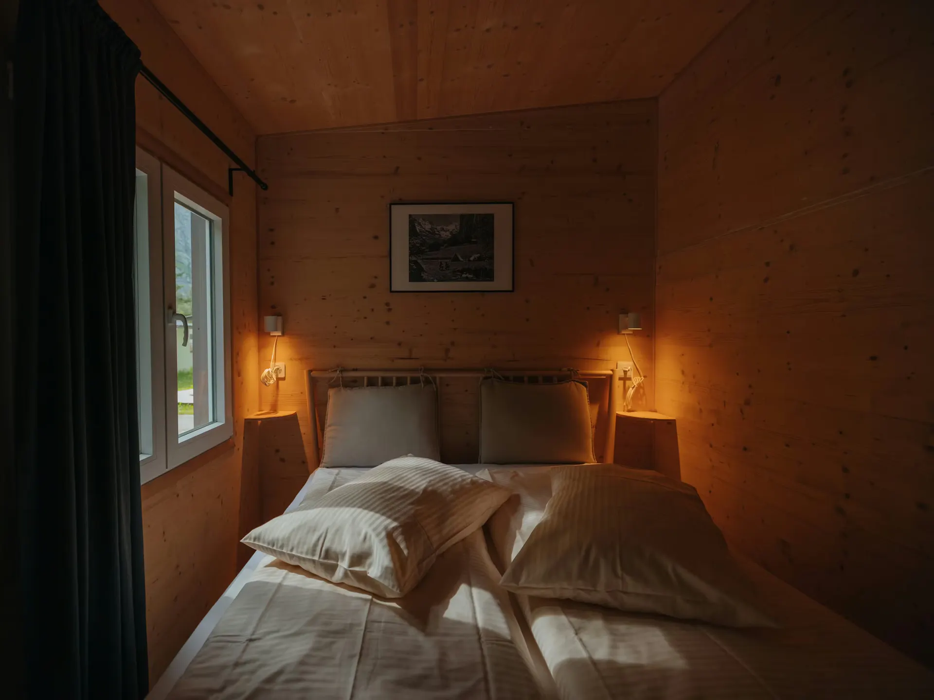 Schlafzimmer mit Holzwänden und bequemem Bett in der Mietunterkunft auf Camping Jungfrau