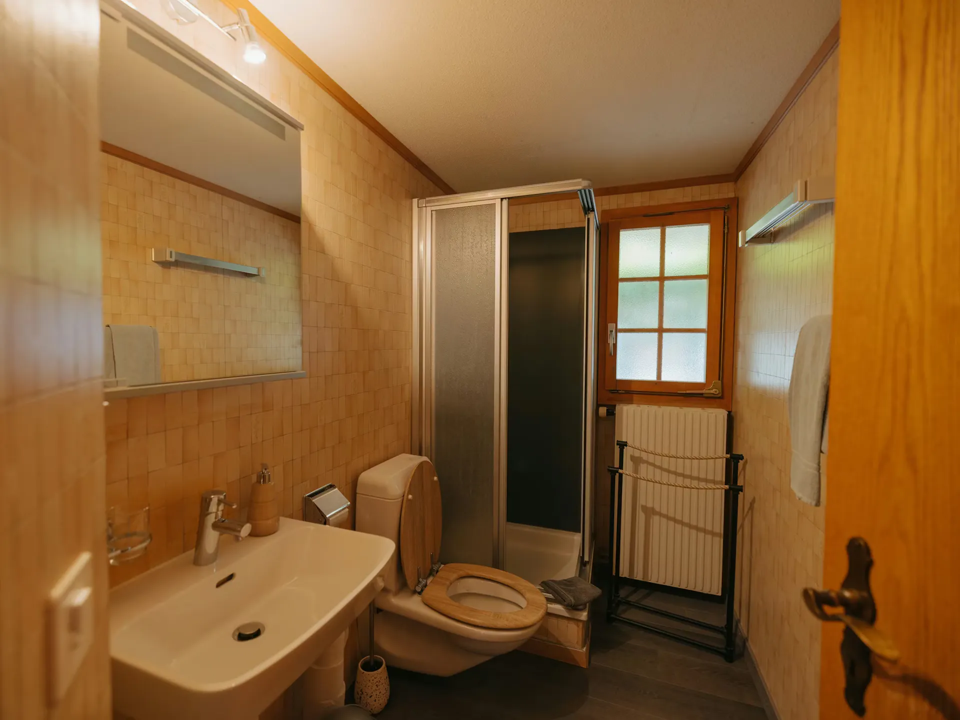 Badezimmer in einem Holz Bungalow mit Waschbecken, Toilette und Dusche