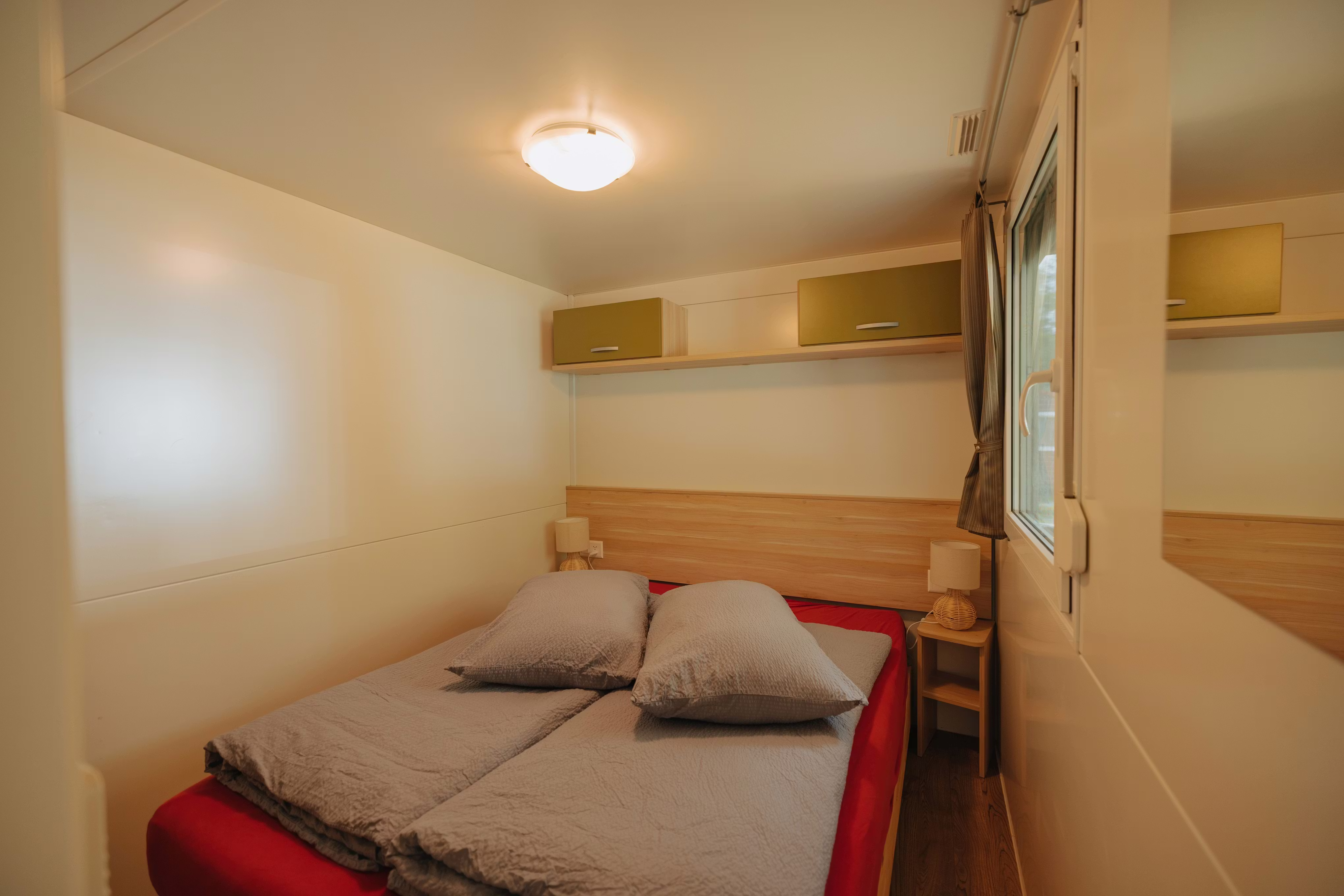 Schlafzimmer des Mobilheims Staubbach mit einem Doppelbett und grauer Bettwäsche
