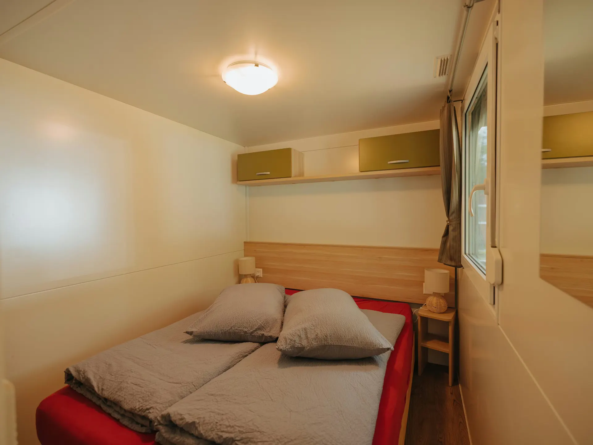 Schlafzimmer des Mobilheims Staubbach mit einem Doppelbett und grauer Bettwäsche