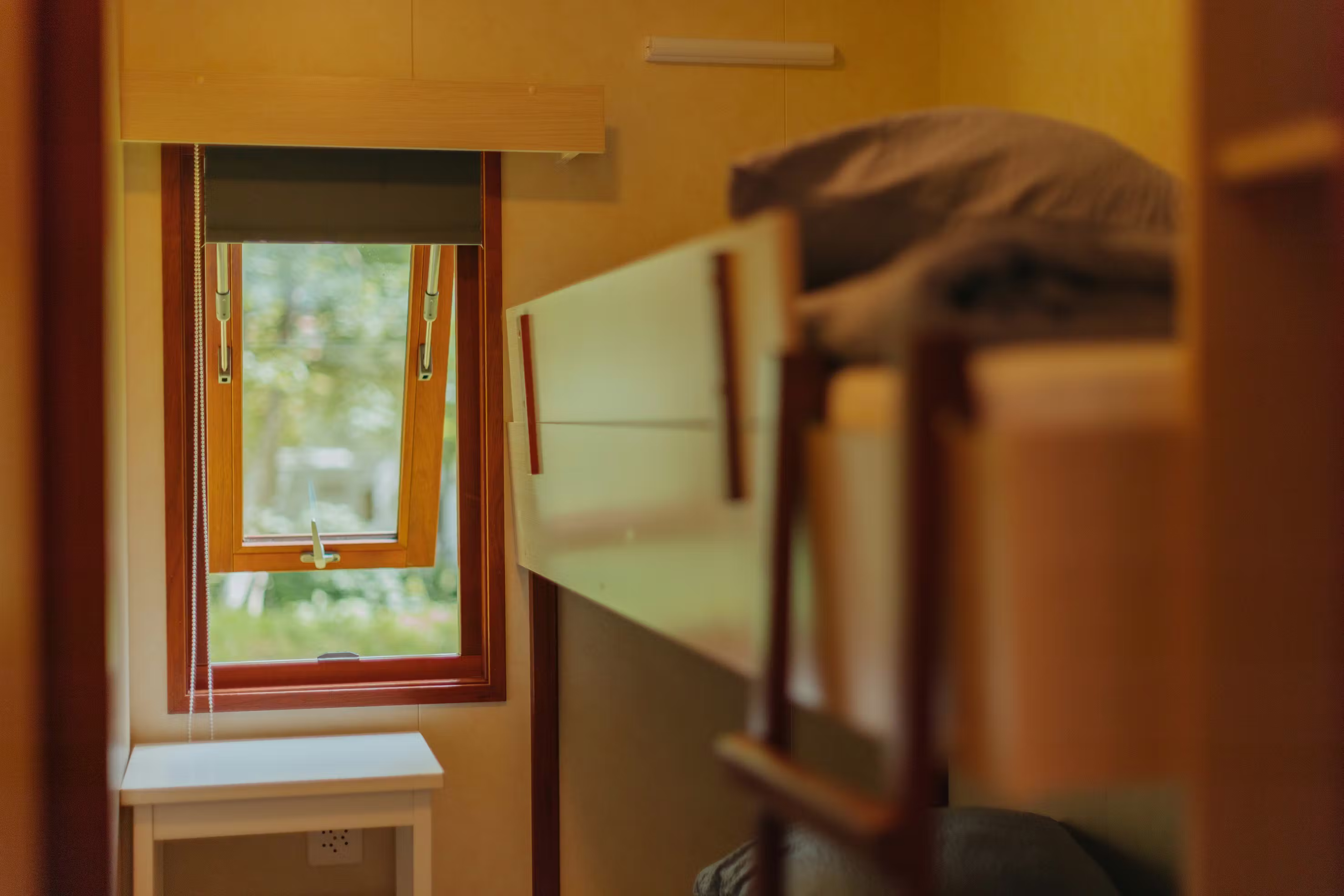 Schlafzimmer des Mobilheims Jungfrau mit einem Etagenbett und einem offenen Fenster am Ende des Zimmers
