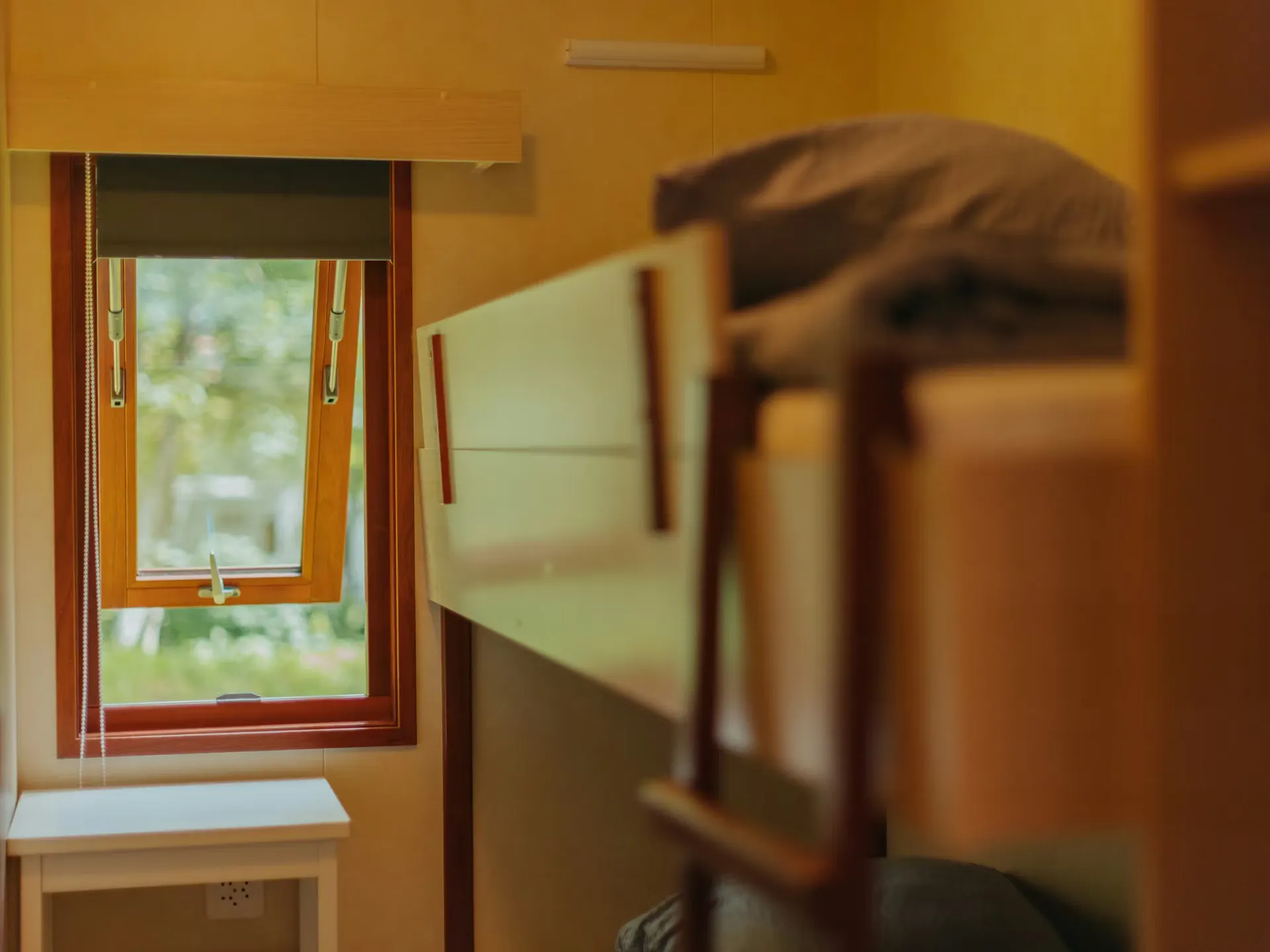 Schlafzimmer des Mobilheims Jungfrau mit einem Etagenbett und einem offenen Fenster am Ende des Zimmers