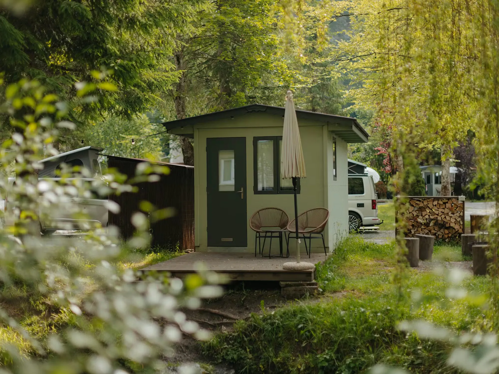 Kleine Hütte, Fuchsbau, auf Camping Jungfrau umgeben von grünen Bäumen und Sträuchern