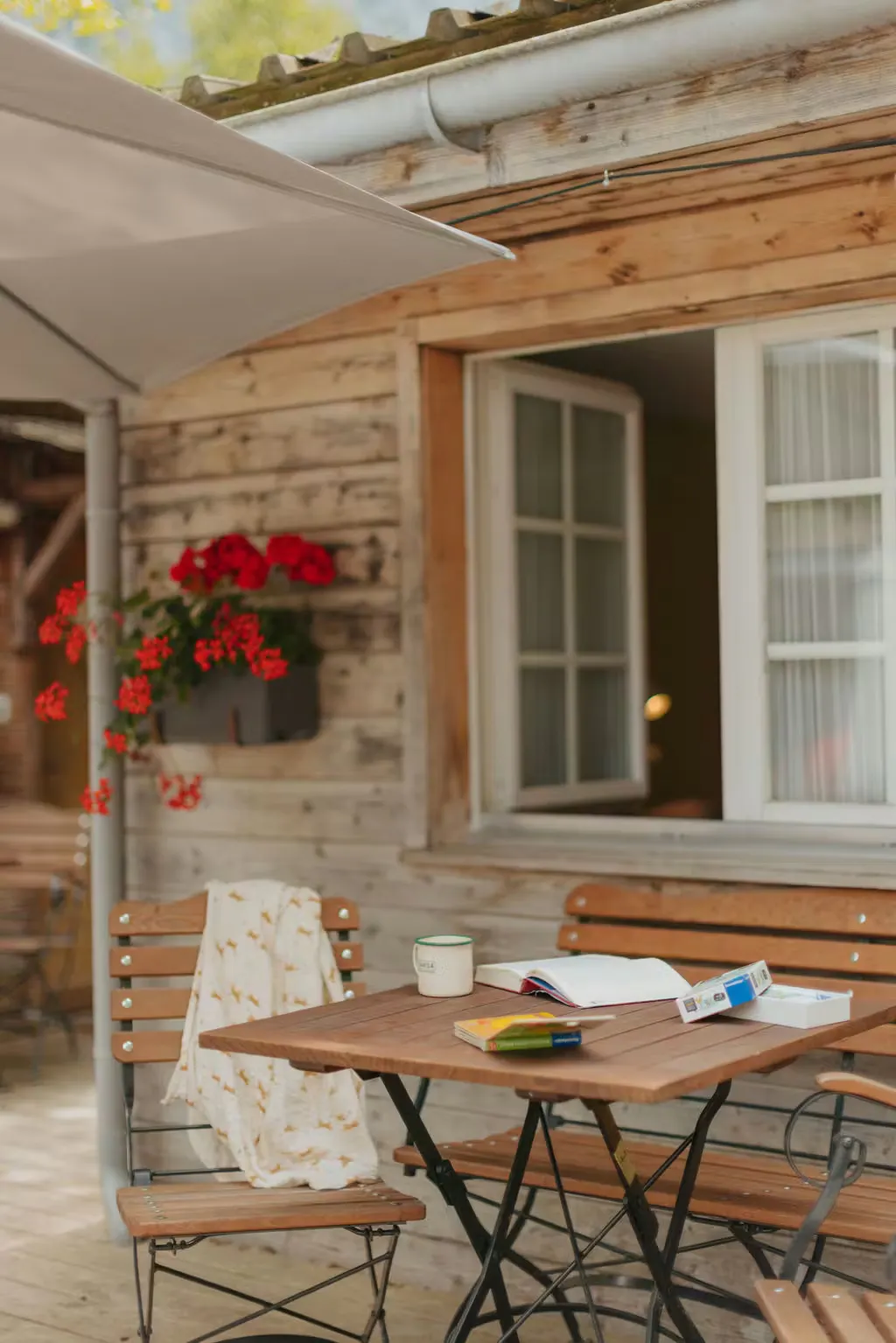 Mesa y silla en la terraza del alojamiento de alquiler «Familienhütte» en el Camping Jungfrau