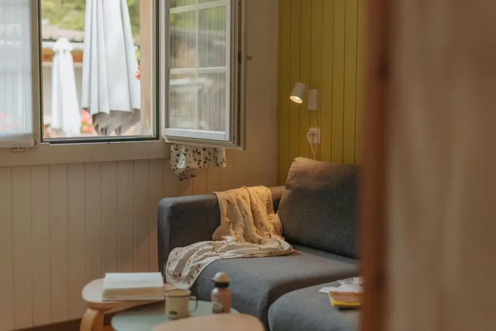 Couch in der Mietunterkunft auf Camping Jungfrau mit Decke und offenem Fenster