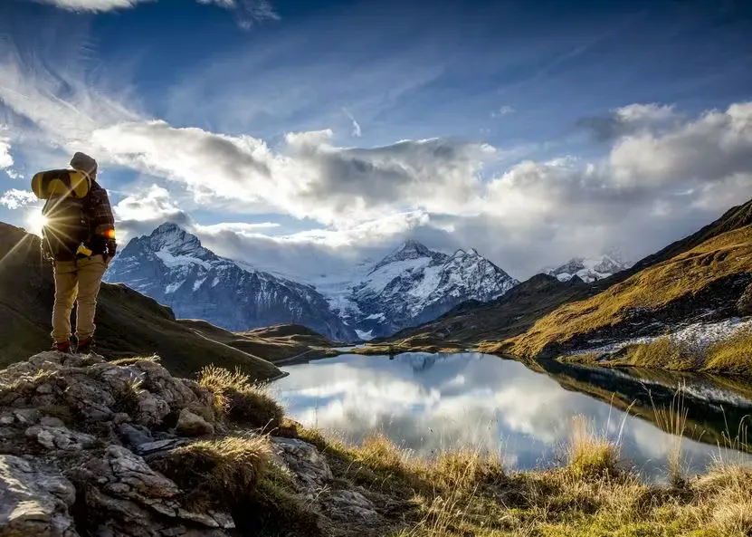 Wanderer neben dem Bachalpsee mit schneebedeckten Bergen im Hintergrund