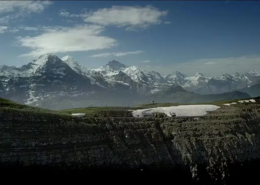 Trailrunner auf dem Eiger Ultra Trail laufen auf einem Bergrücken mit schneebedeckten Bergen im Hintergrund