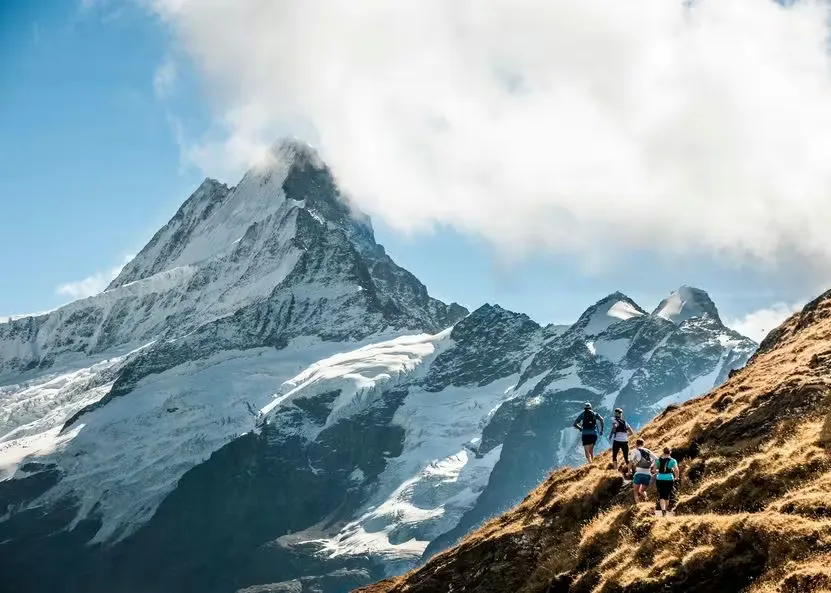 Trailrunner auf dem Eiger Ultra Trail in den Berner Bergen mit schneebedeckten Bergen im Hintergrund