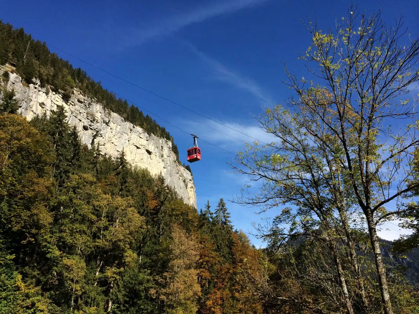 Rote Bergbahn nach Isenfluh und Sulwald mit Felswänden im Hintergrund und blauem Himmel