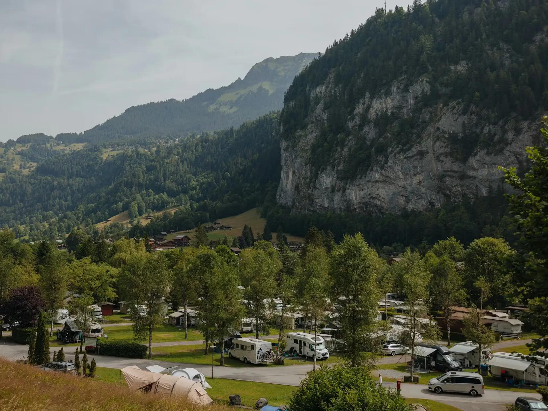 Campingplatz mit Wohnmobilen im Sommer und Bergen dahinter