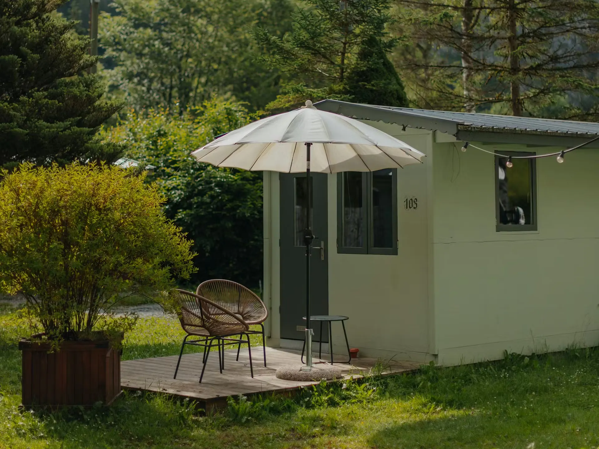 Mietunterkunft Fuchsbau für zwei Personen mit Terrasse, zwei Stühlen und einem Sonnenschirm