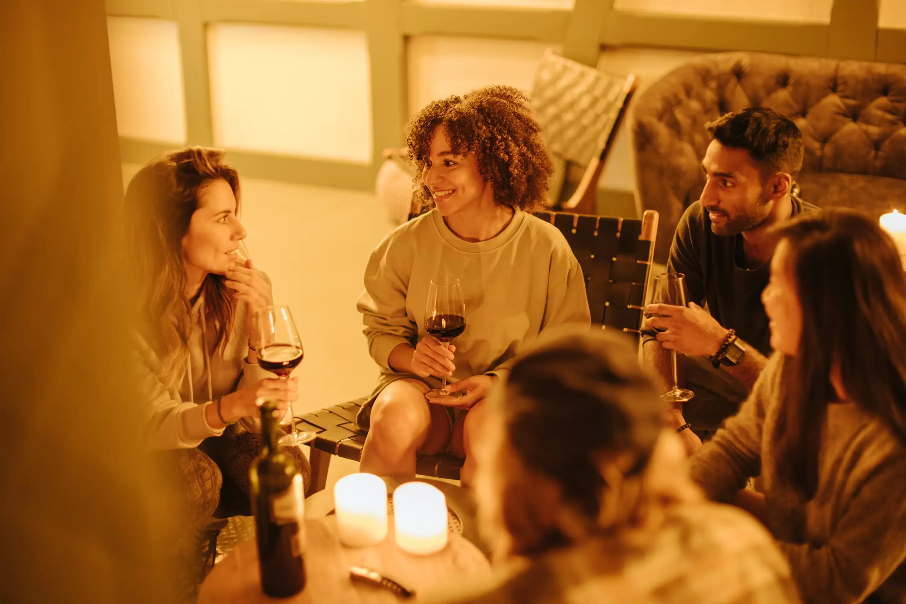 Camperinnen und Camper sitzen mit einem Glas Wein in der Hand in der Lounge des Camping Jungfrau und geniessen einen Abend mit guten Gesprächen