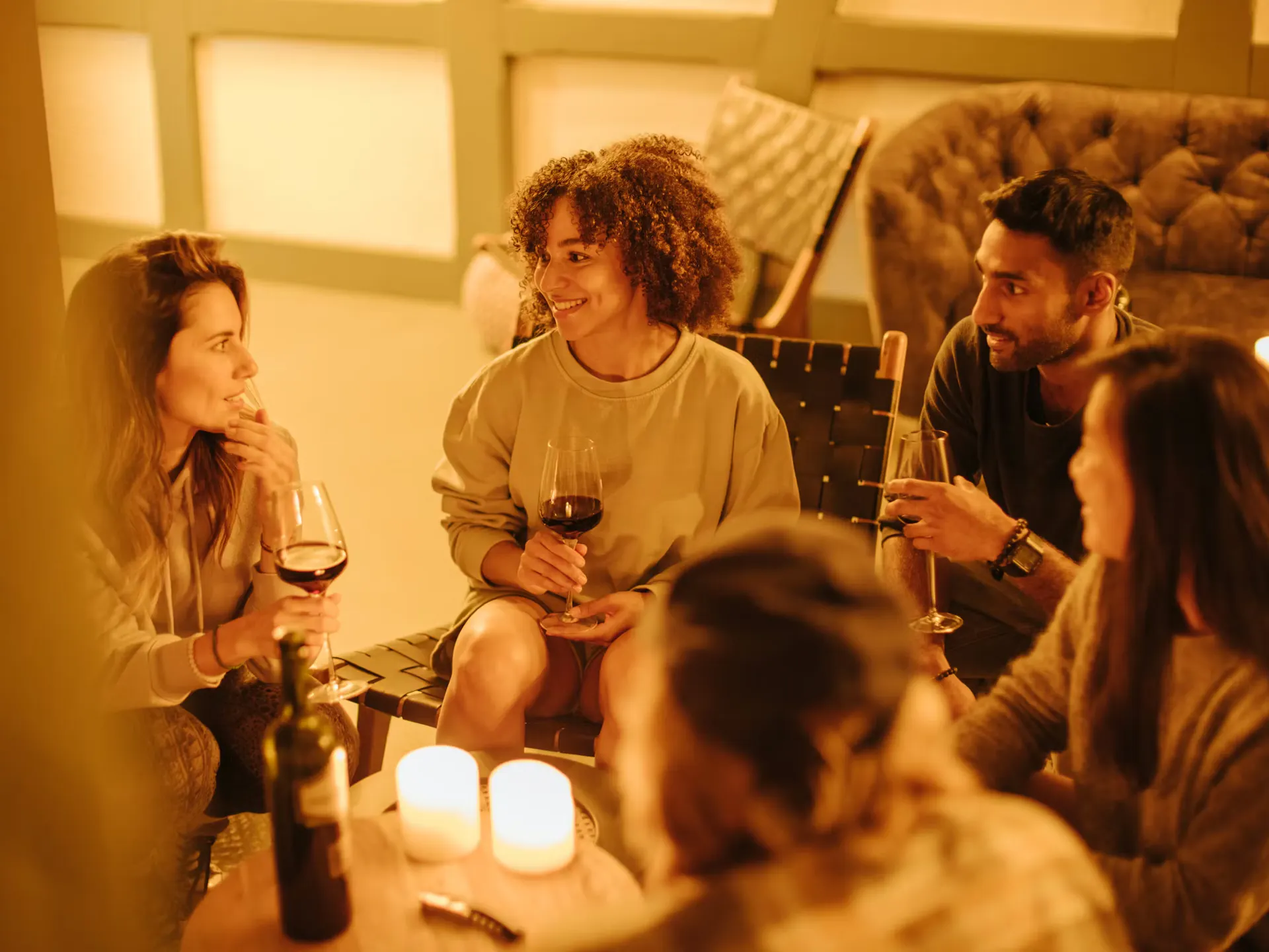 Camperinnen und Camper sitzen mit einem Glas Wein in der Hand in der Lounge des Camping Jungfrau und geniessen einen Abend mit guten Gesprächen