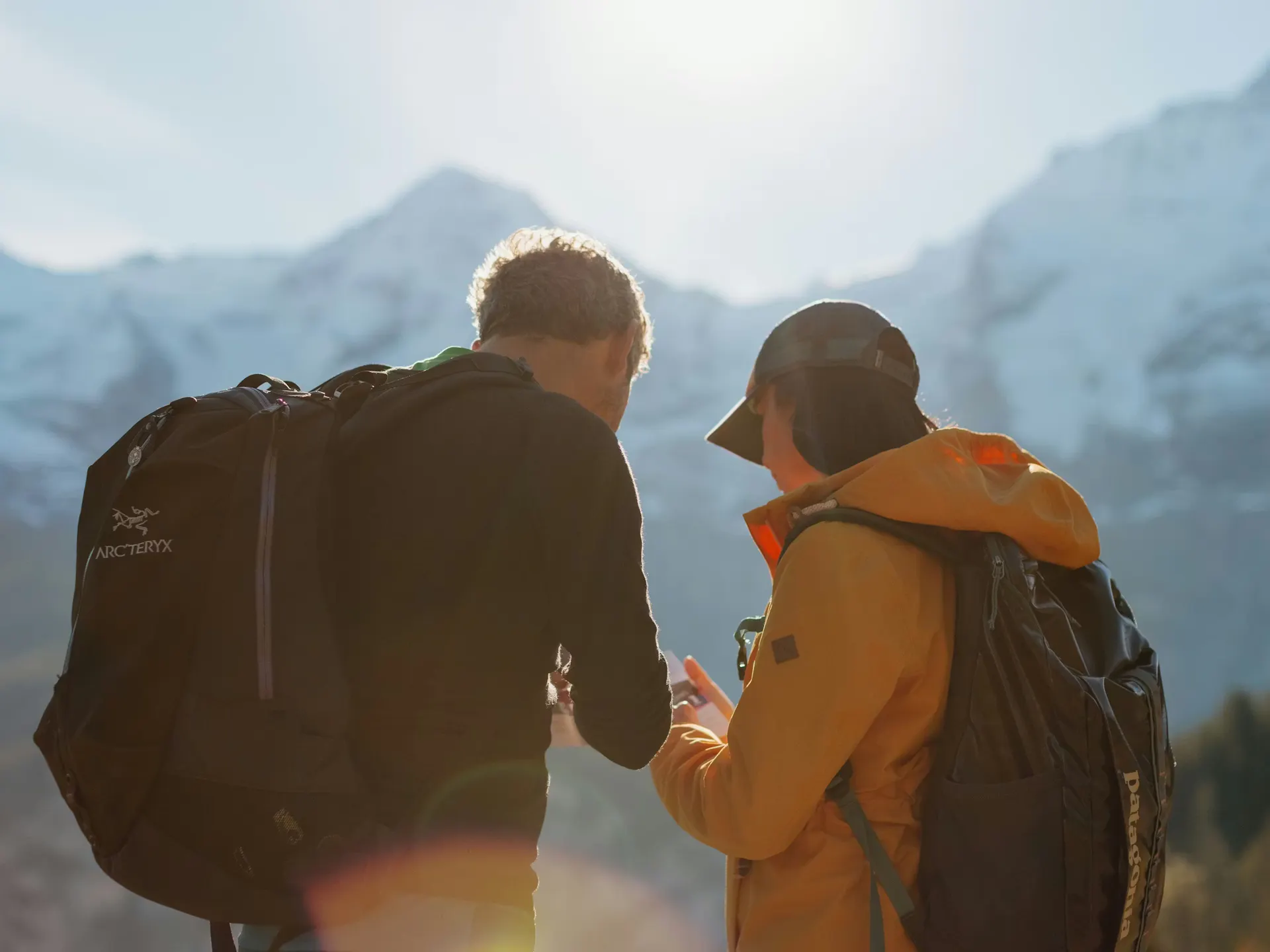 Wanderer mit Blick auf eine Karte mit den Bergen Eiger, Mönch und Jungfrau im Hintergrund