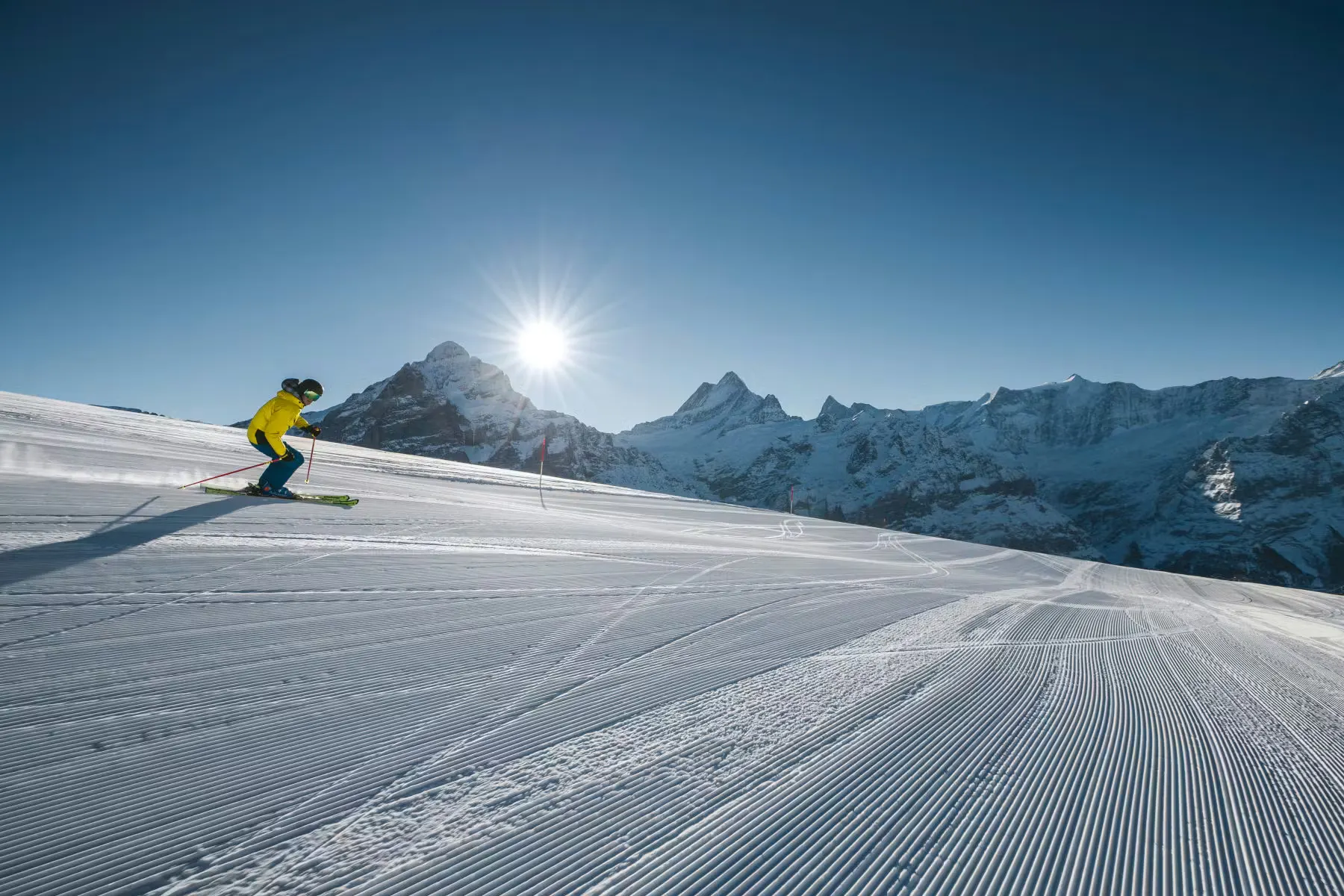 Skifahrer auf Skipiste in der Jungfrau Region mit blauem Himmel