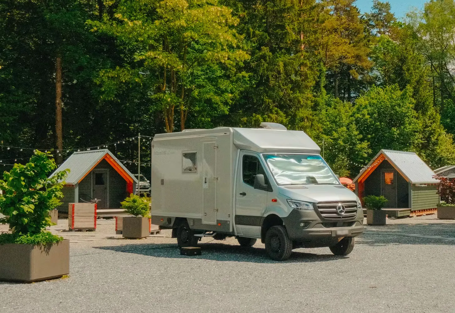 Camper auf einem Classic Stellplatz auf dem Camping Bad Ragaz mit blauem Himmel und Alphütten im Hintergrund