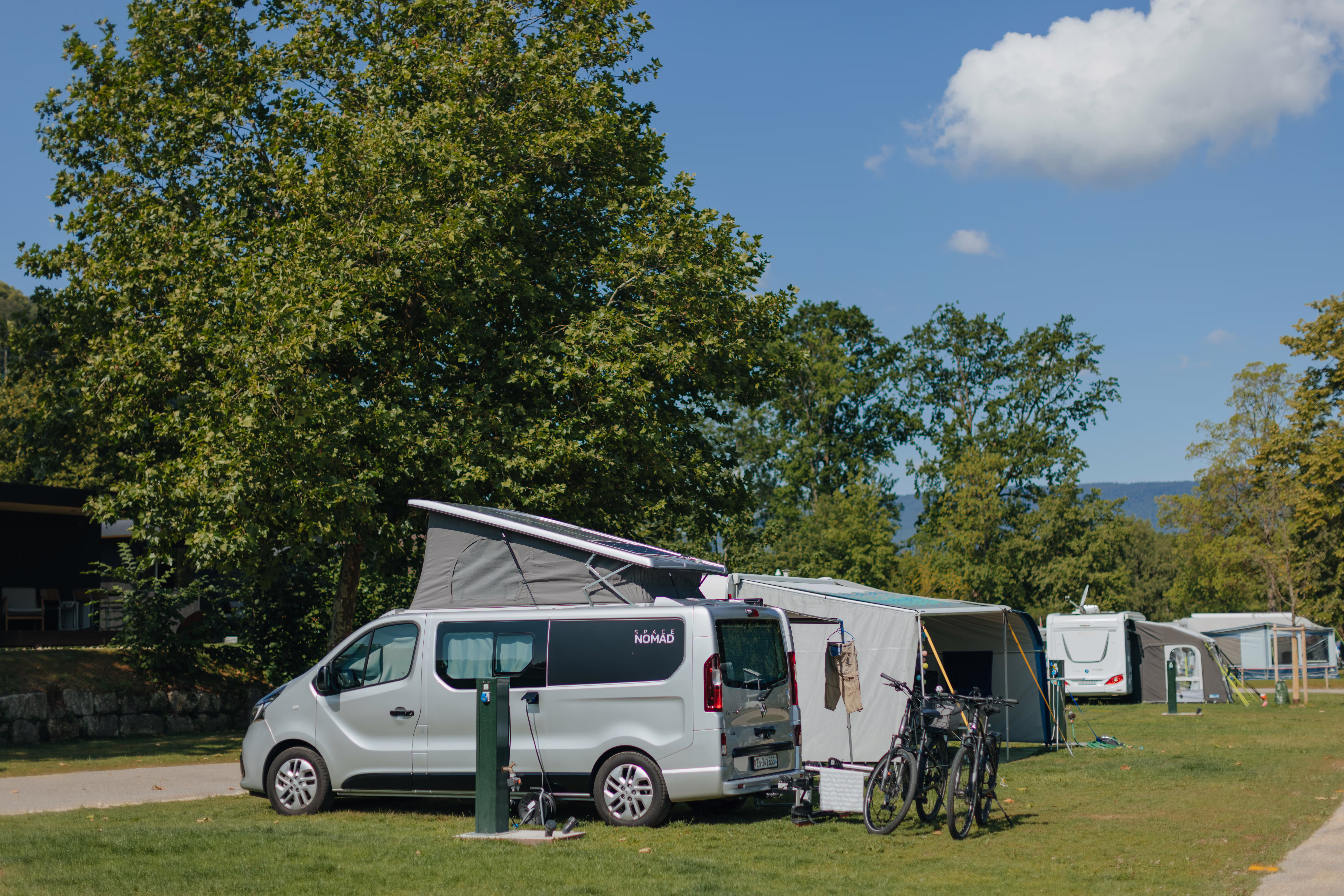 Ein Van und ein Wohnwagen mit Vorzelt auf einem Stellplatz Classic am See auf Camping Erlach