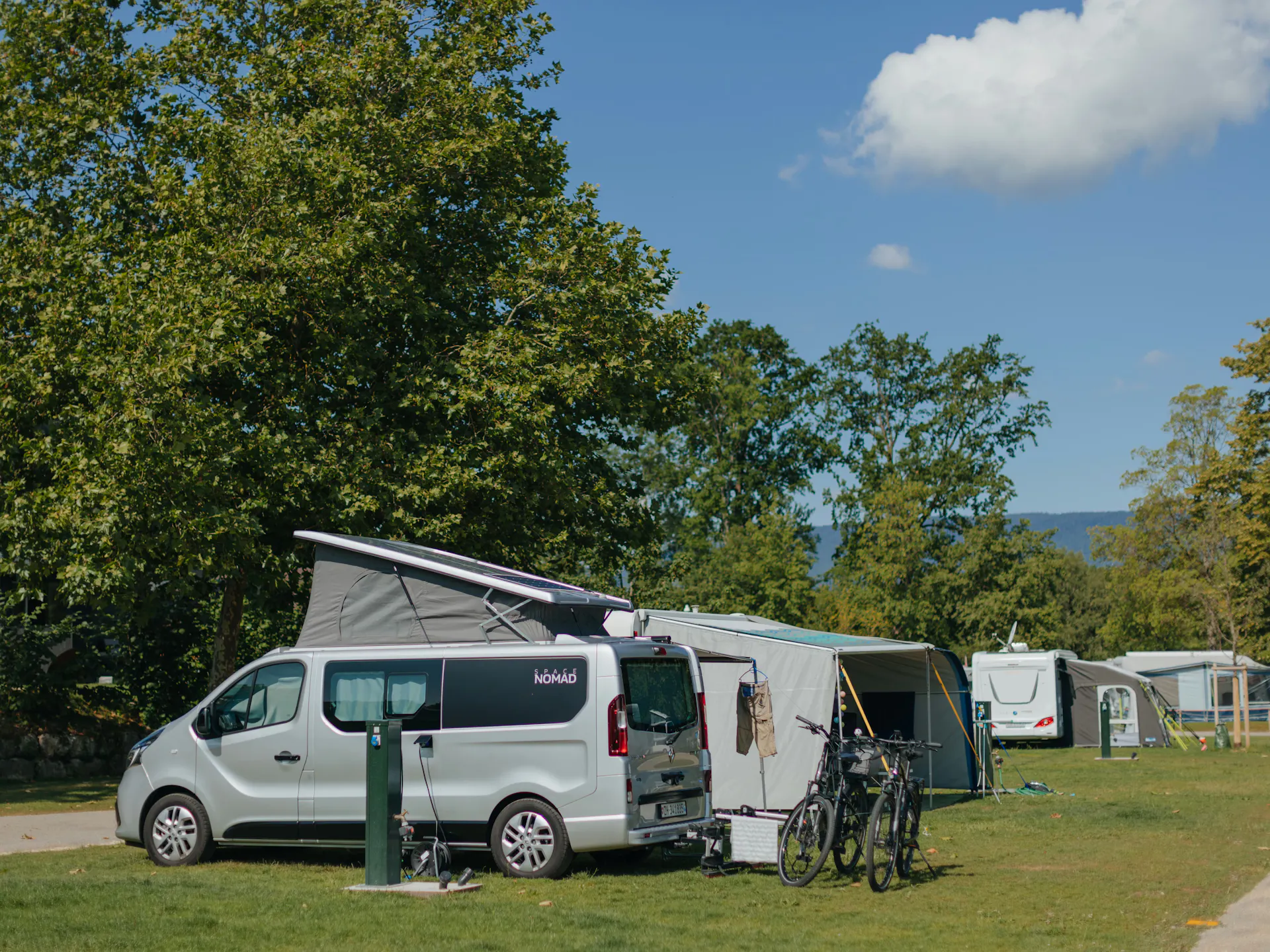 Ein Van und ein Wohnwagen mit Vorzelt auf einem Stellplatz Classic am See auf Camping Erlach