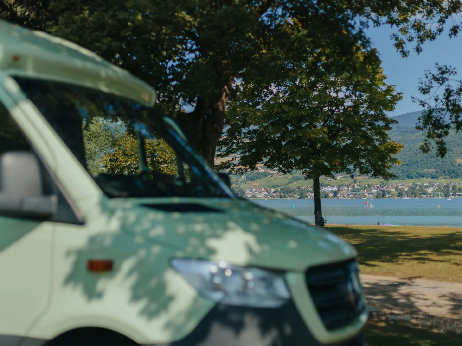 Front eines Vans auf einem Stellplatz mit Blick auf den Bielersee im Hintergrund an einem Sommertag