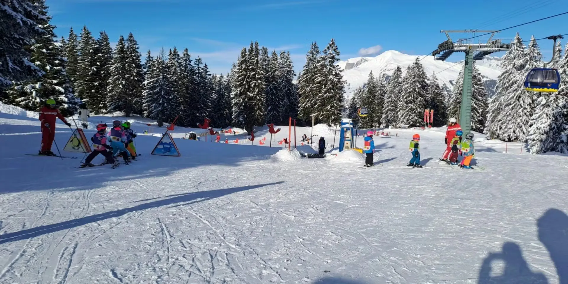 Kinderskilift mit vielen Kindern am Skifahren in Grüsch-Danusa mit Gondelbahn oberhalb