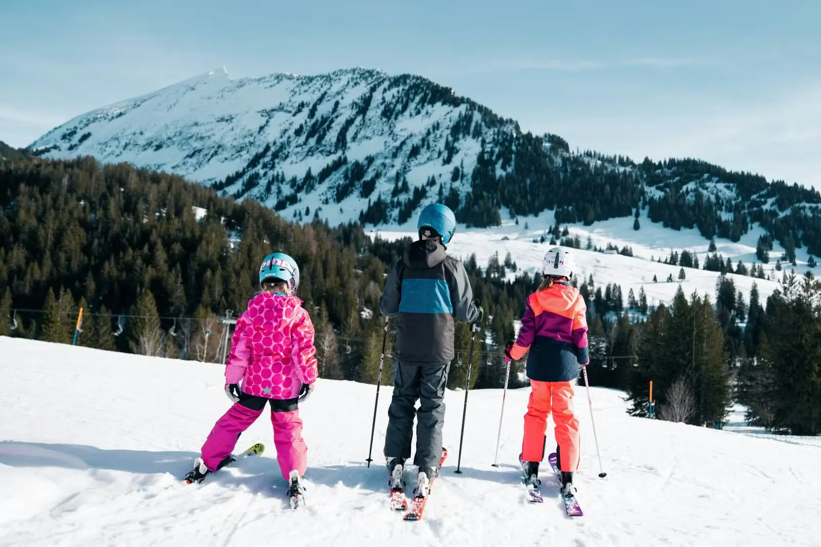 Drei Kinder im Skigebiet Amden Arvenbüel blicken in Richtung Leistkamm zum Rücken gedreht