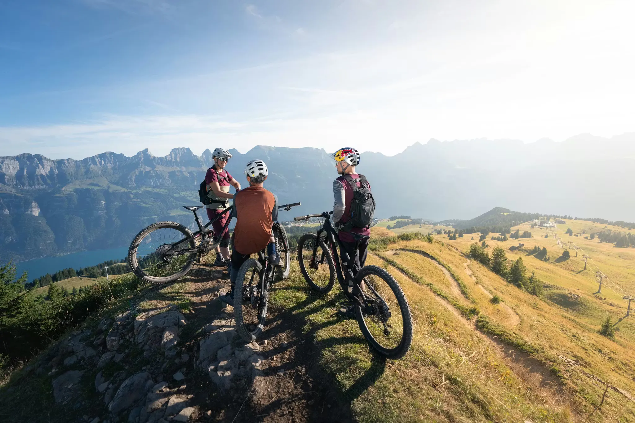 Drei Mountainbiker auf einem Mountainbike-Trail in den Bergen bei Flumserberg, mit See und Bergen im Hintergrund