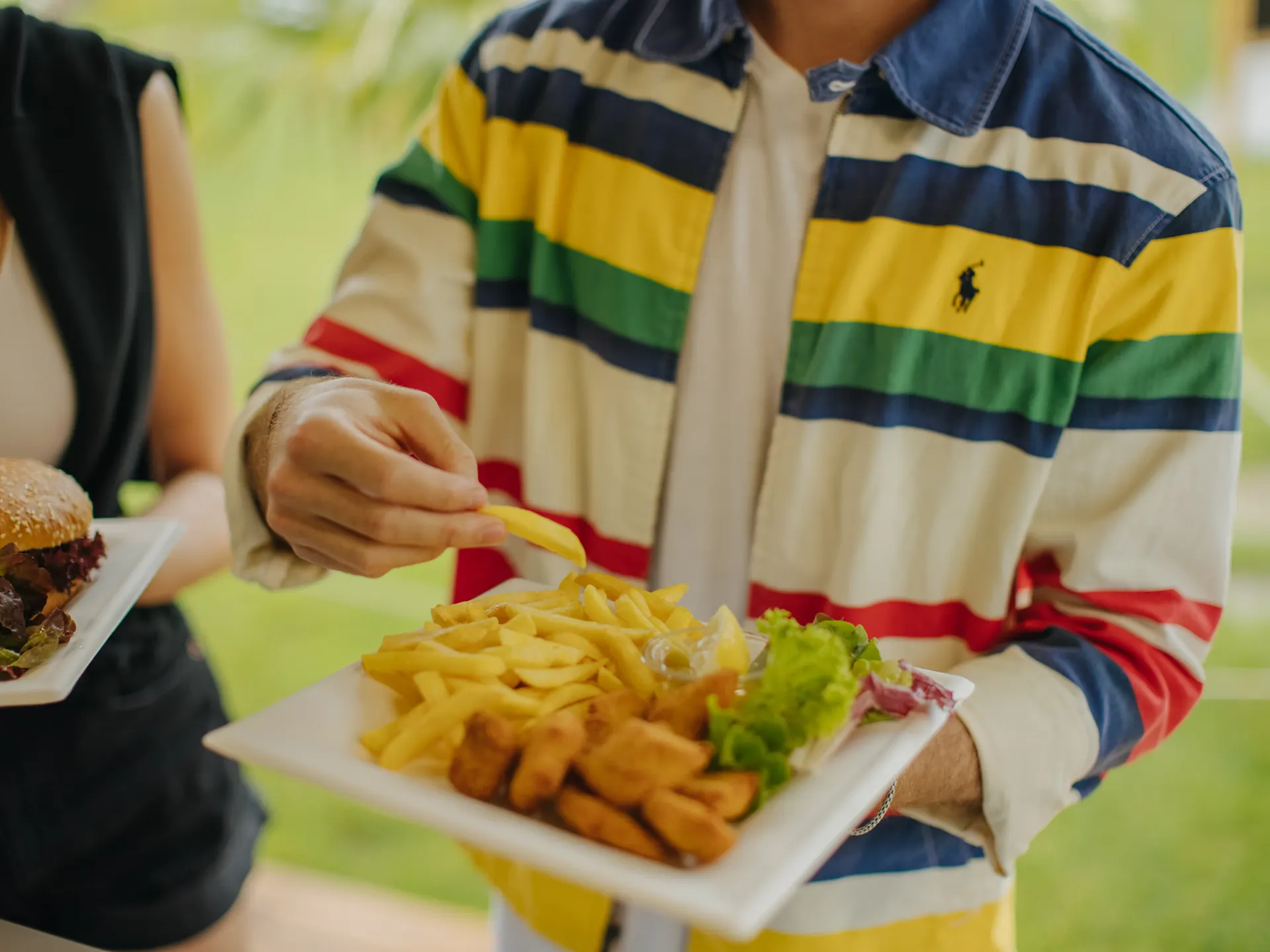 Person mit Fischknusperli und Pommes der Strandchuchi, Foodtruck vom Camping Erlach am Bielersee