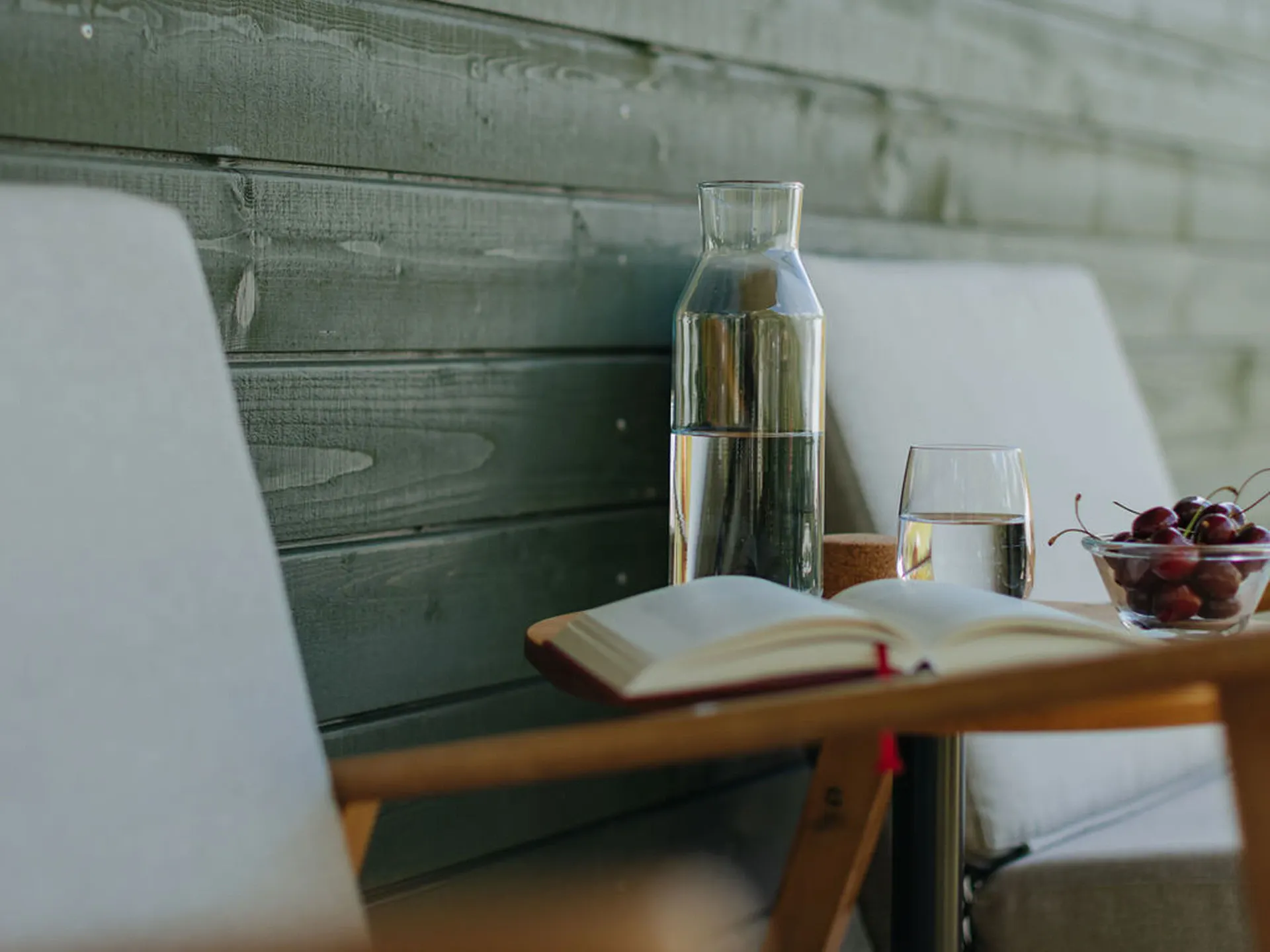 Stühle und ein Tisch mit einem Buch, Wasser und Kirschen auf der Terrasse der Mietunterkunft auf Camping Erlach