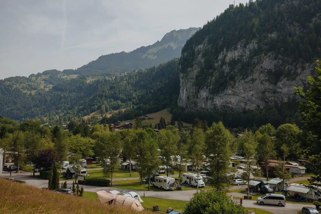 campsite with campervans in the summer and mountains behind it