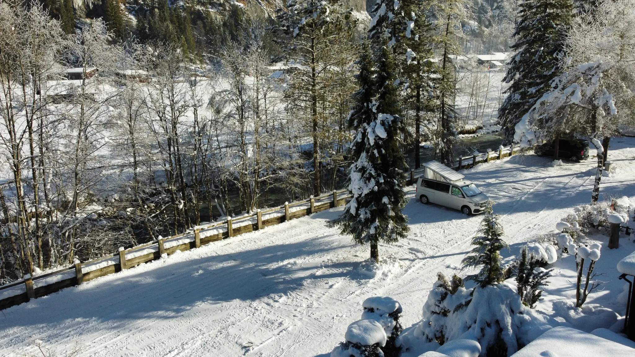 Drohnenaufnahme des Campingplatzes Jungfrau im Winter mit einem Lieferwagen auf einem verschneiten Stellplatz